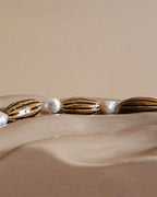 Close-up of a choker with pearls and gold accents on a beige background