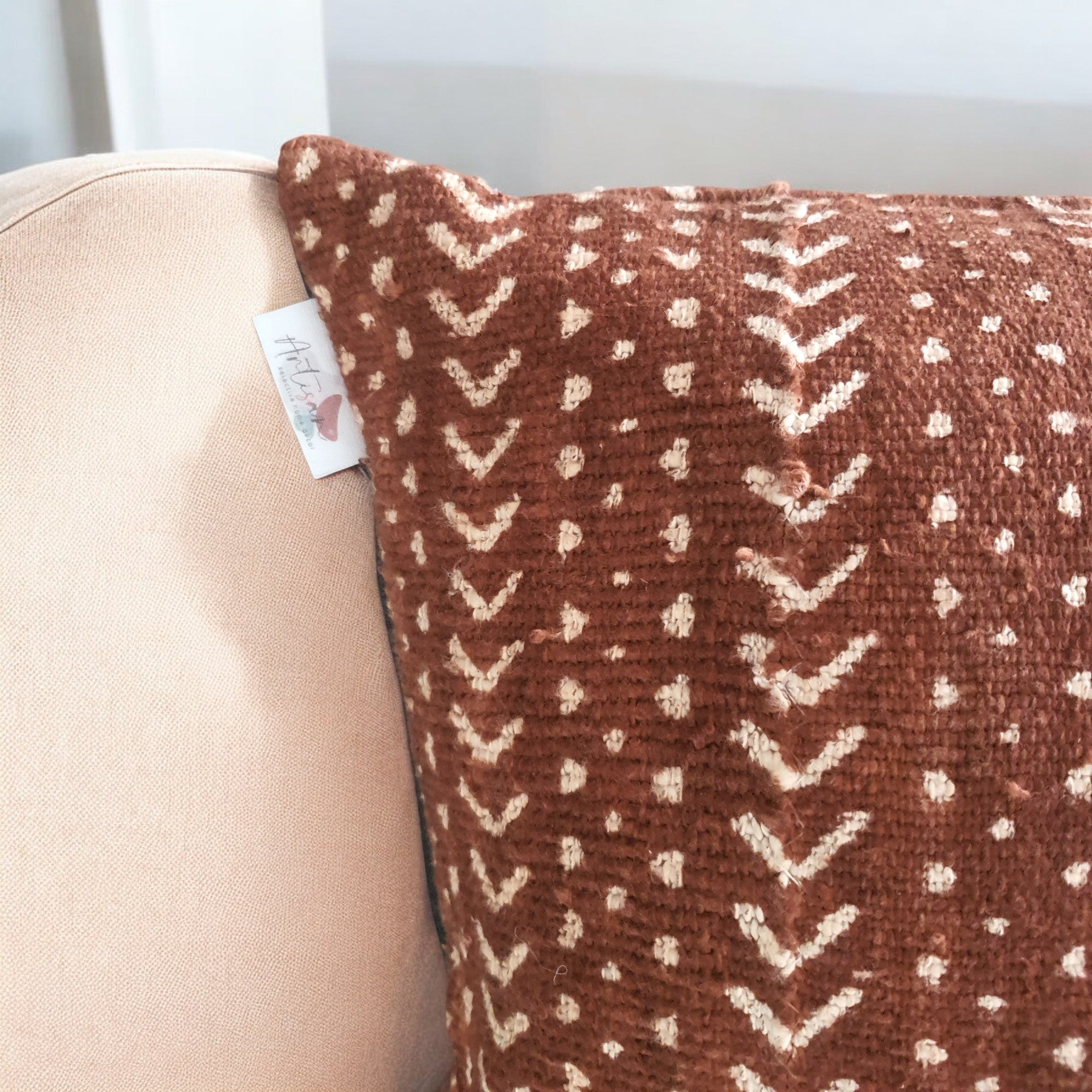 Brown pillow with white pattern on a beige couch