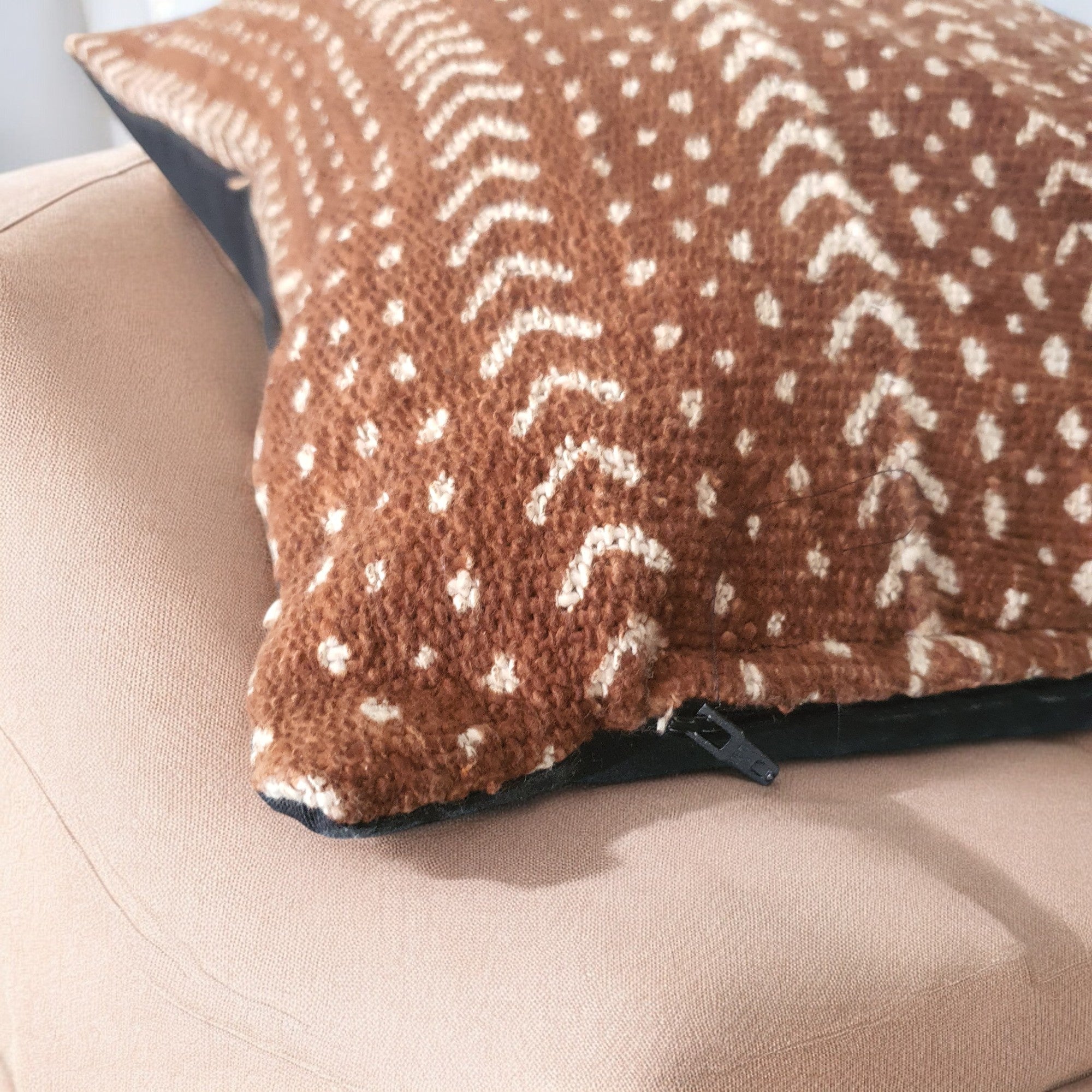 Brown pillow with white pattern on a beige couch