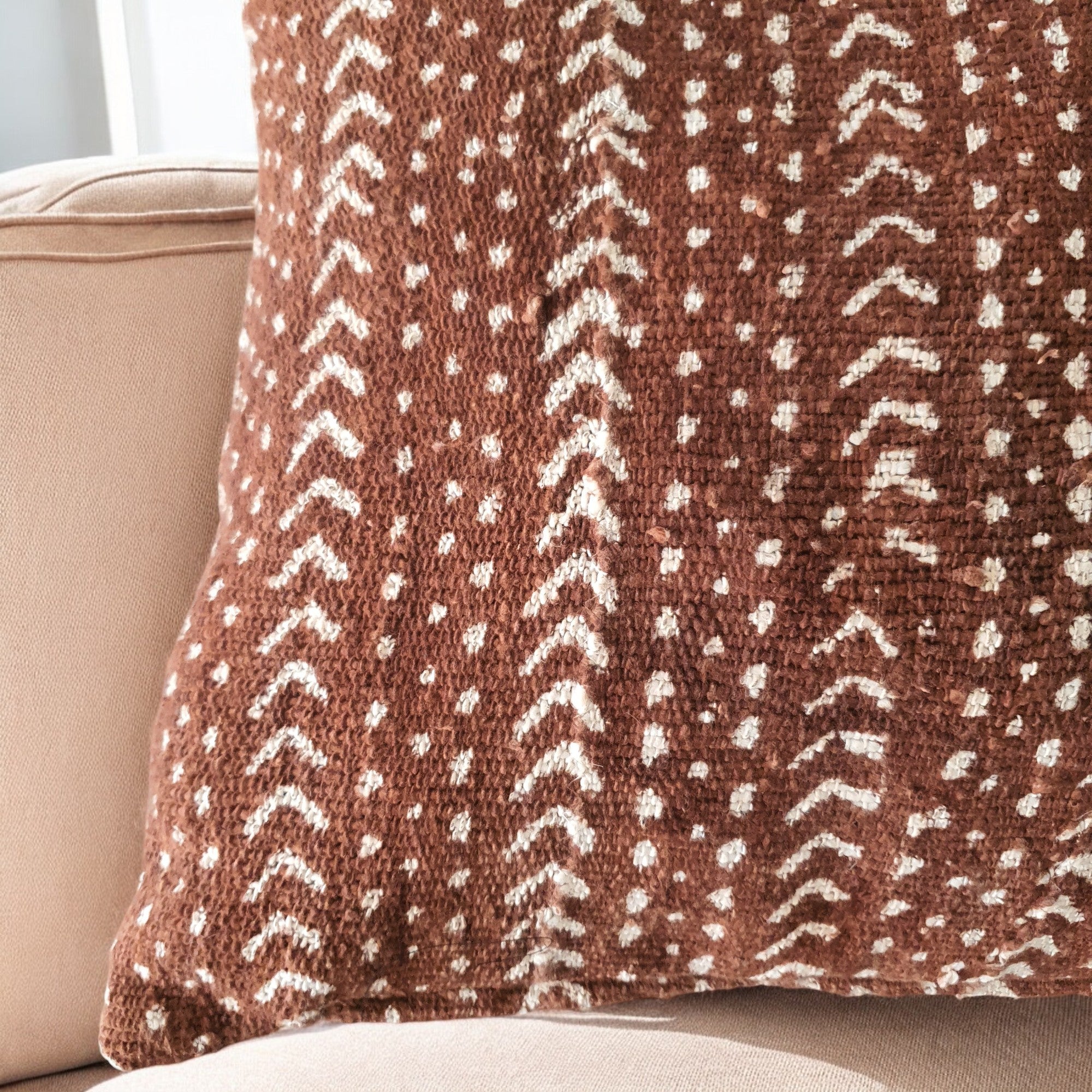 Brown pillow with white pattern on a beige couch