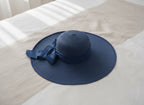 Blue straw hat with a bow on a bed
