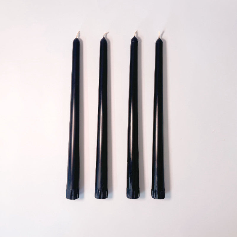 Four black candles lined up on a white background