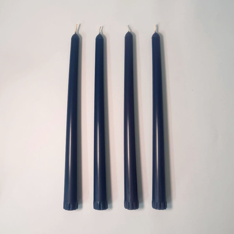 Four navy blue candles of varying heights on a white background