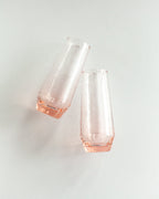 Two blush glass flutes on a light gray background