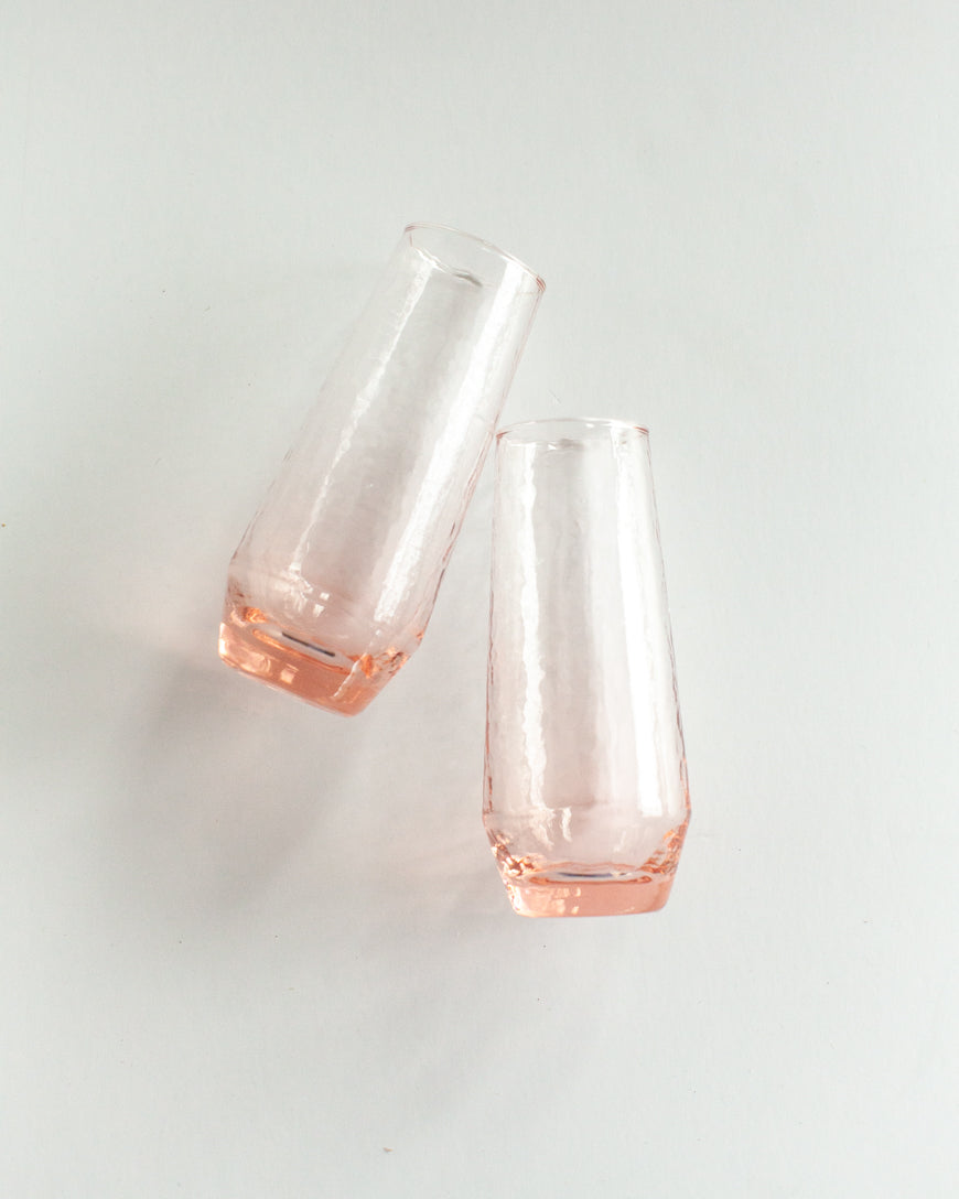 Two blush glass flutes on a light gray background
