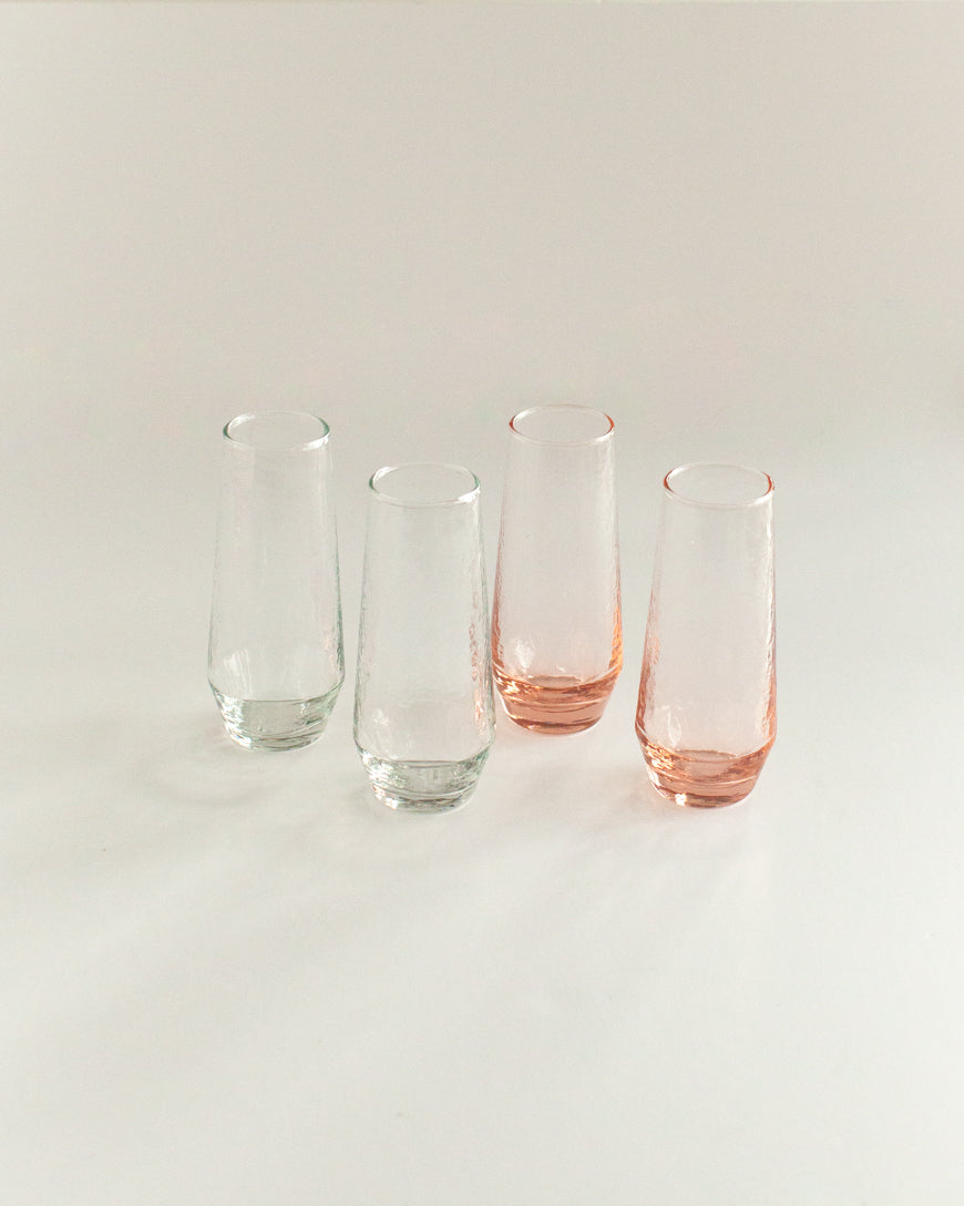 Four glass tumblers with pink and clear designs on a light gray background