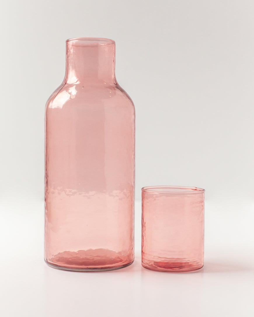 Pink glass carafe and tumbler on a light gray background
