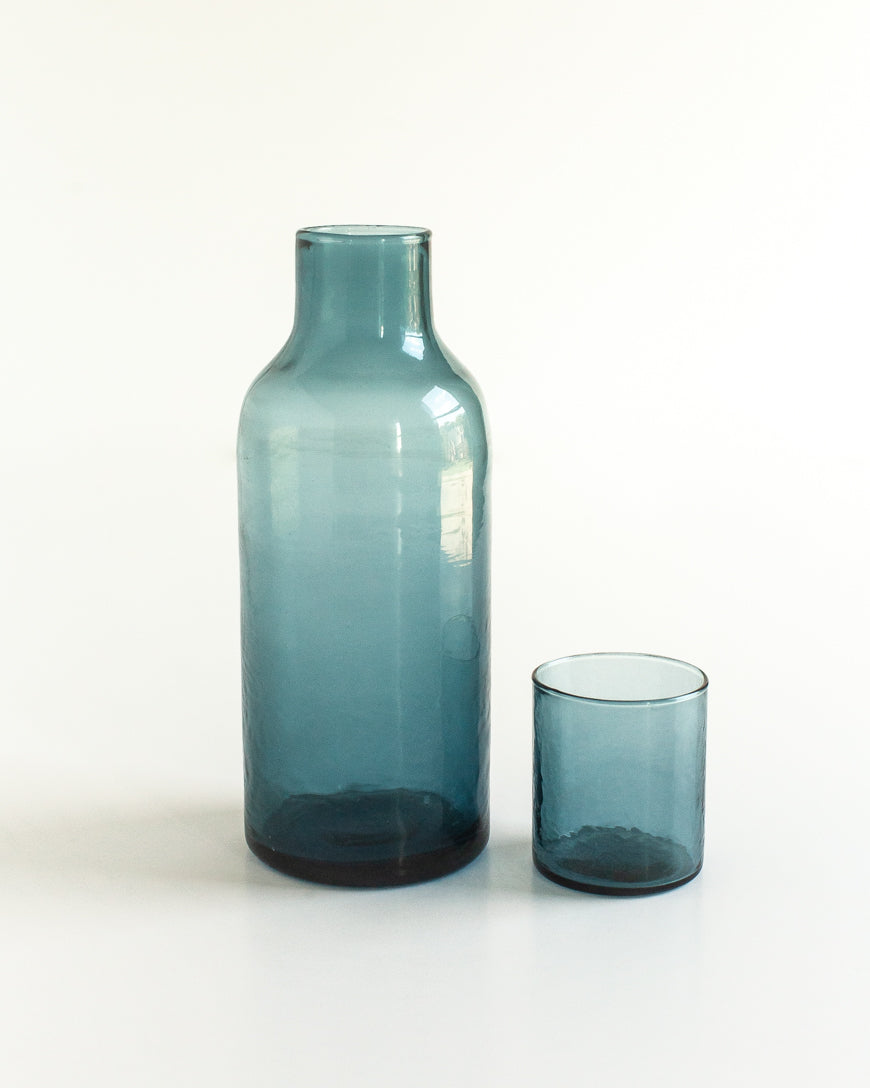 Blue glass bottle and cup on a white background