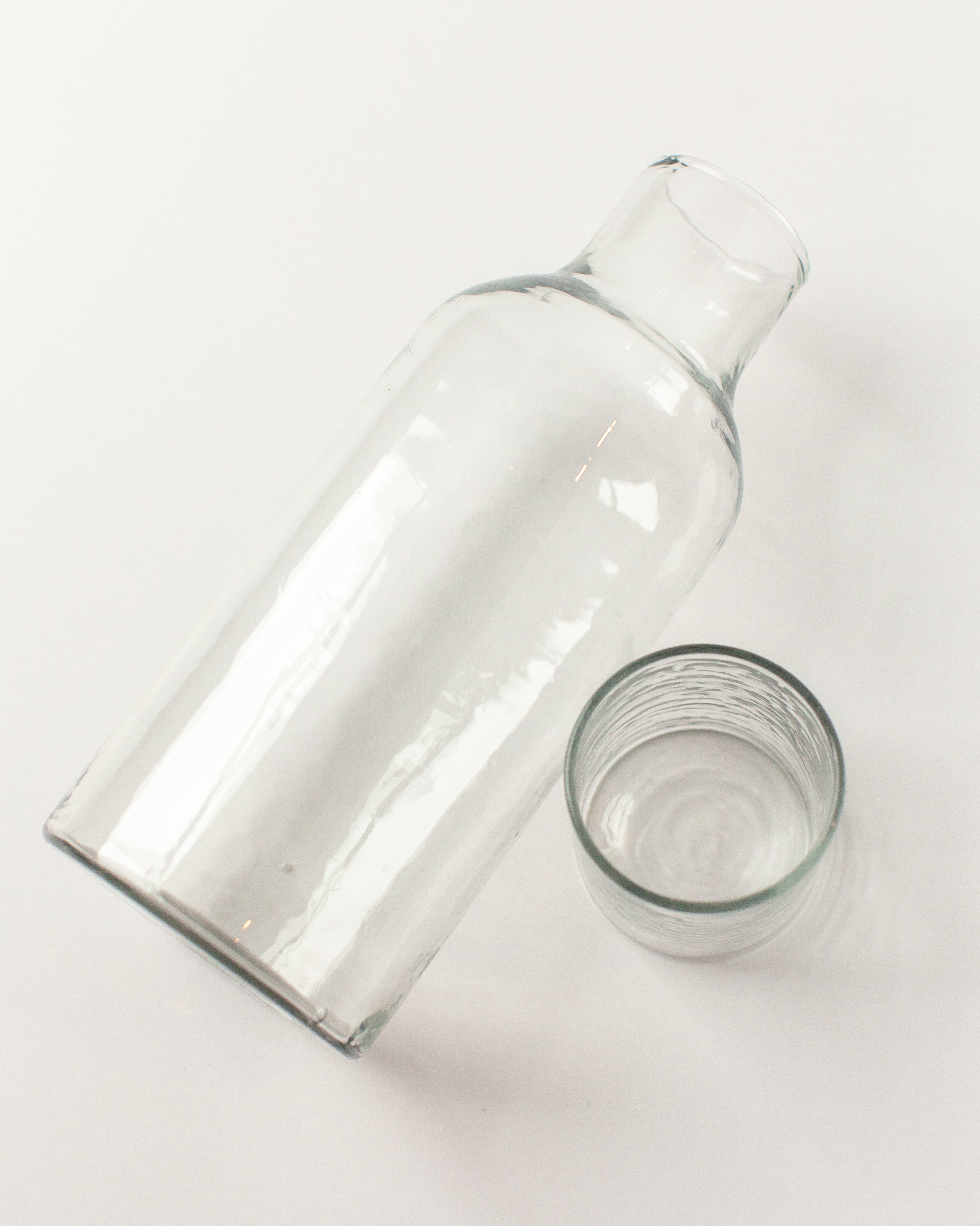 Clear glass bottle and tumbler on a white background