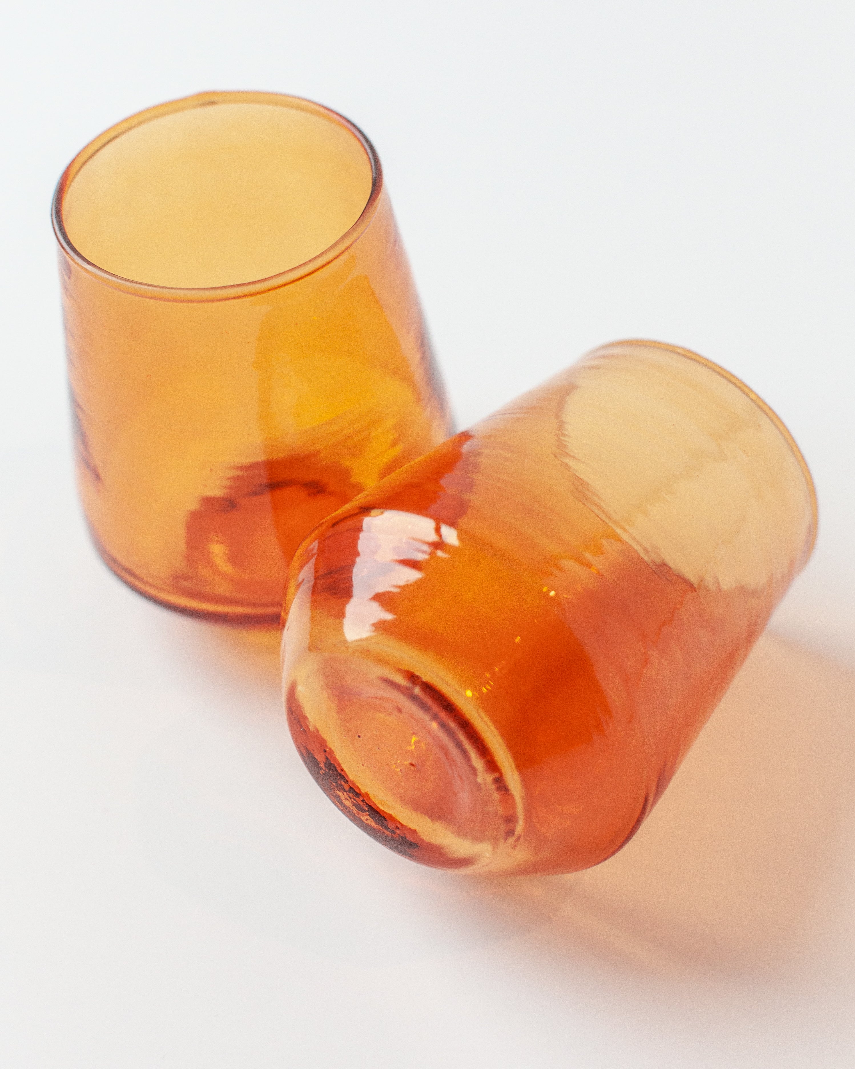 Two amber-colored glass tumblers on a white background