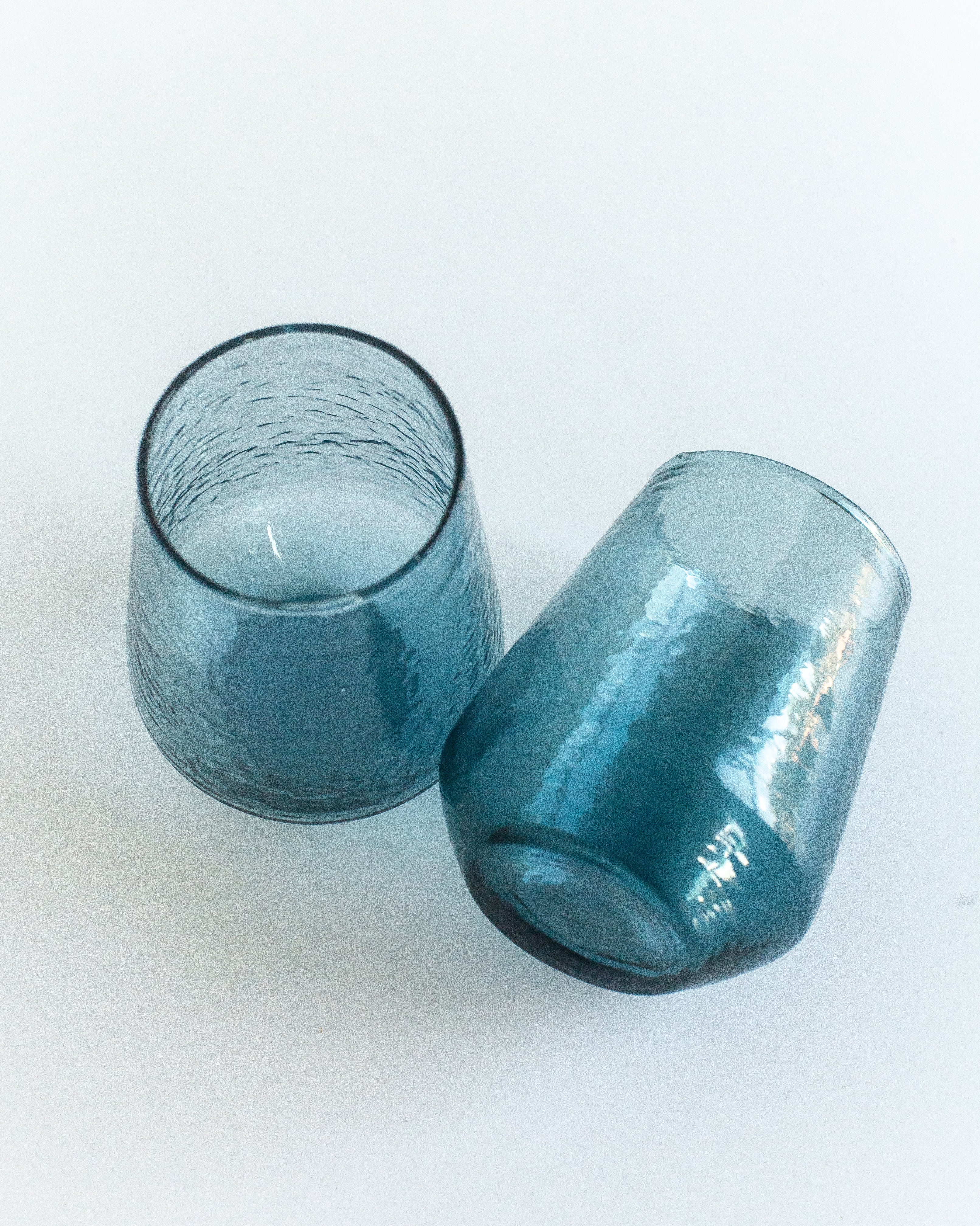 Two blue glass tumblers on a white background