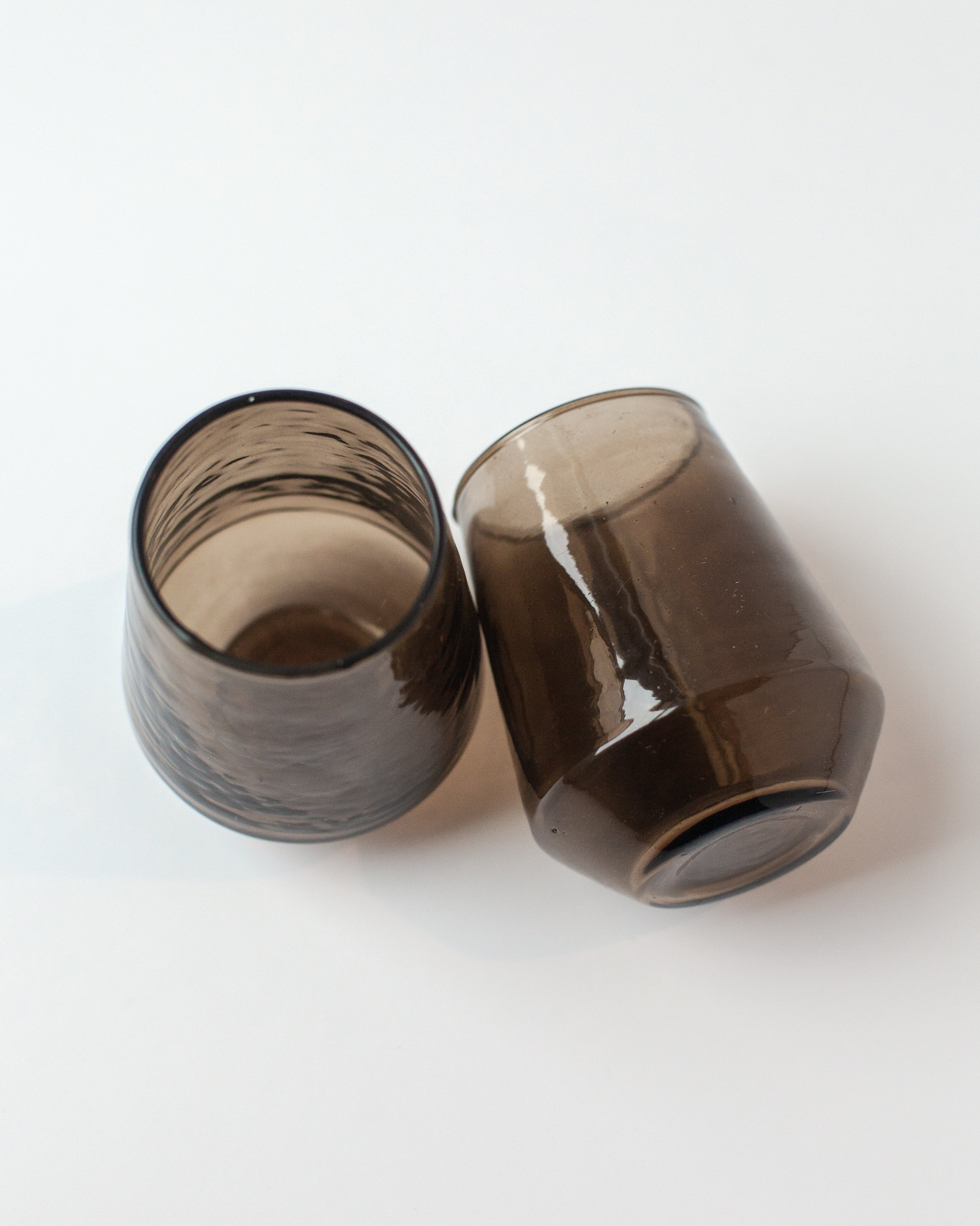 Two smoked glass tumblers on a white background
