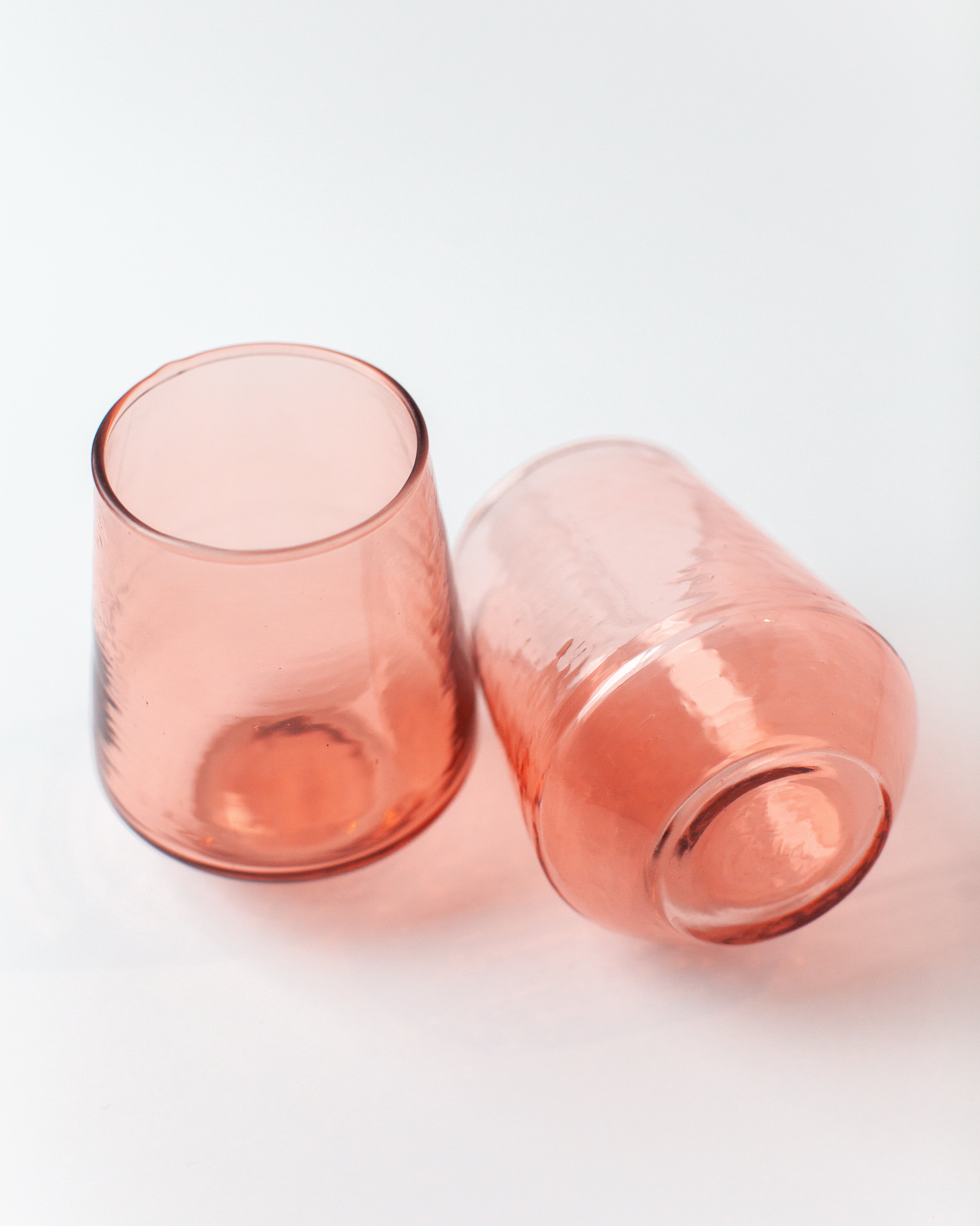 Two pink glass tumblers on a white background