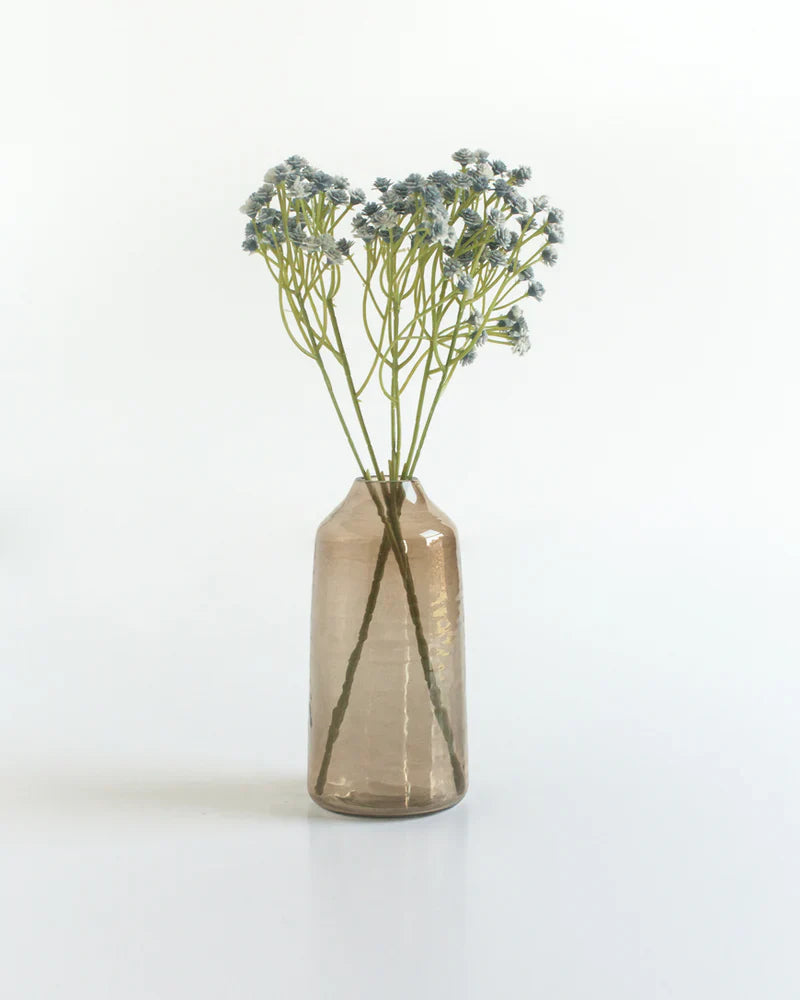 Small clear vase with dried flowers on a white background