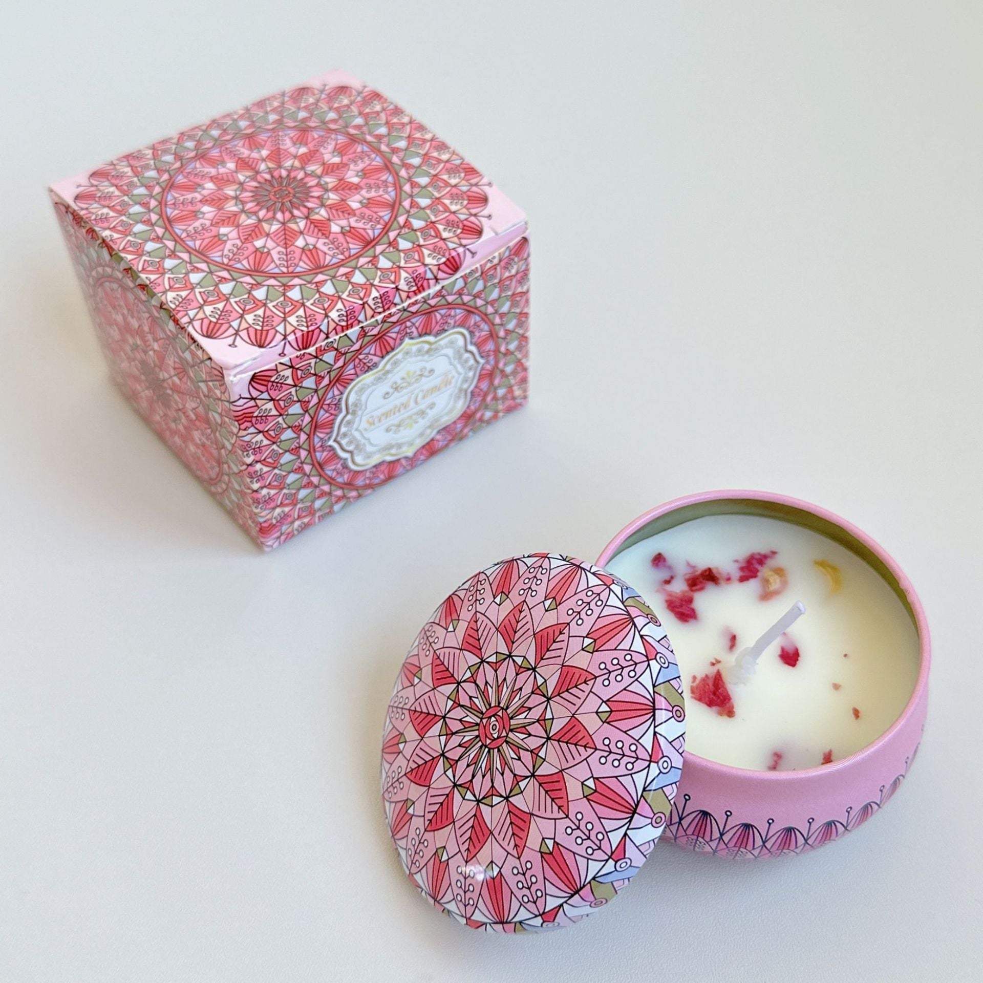 Candle in a decorative pink box with mandala design on a white background