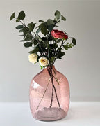 Pink glass vase with flowers on a light background