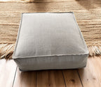 Gray cushion on a wooden floor with a woven rug in the background
