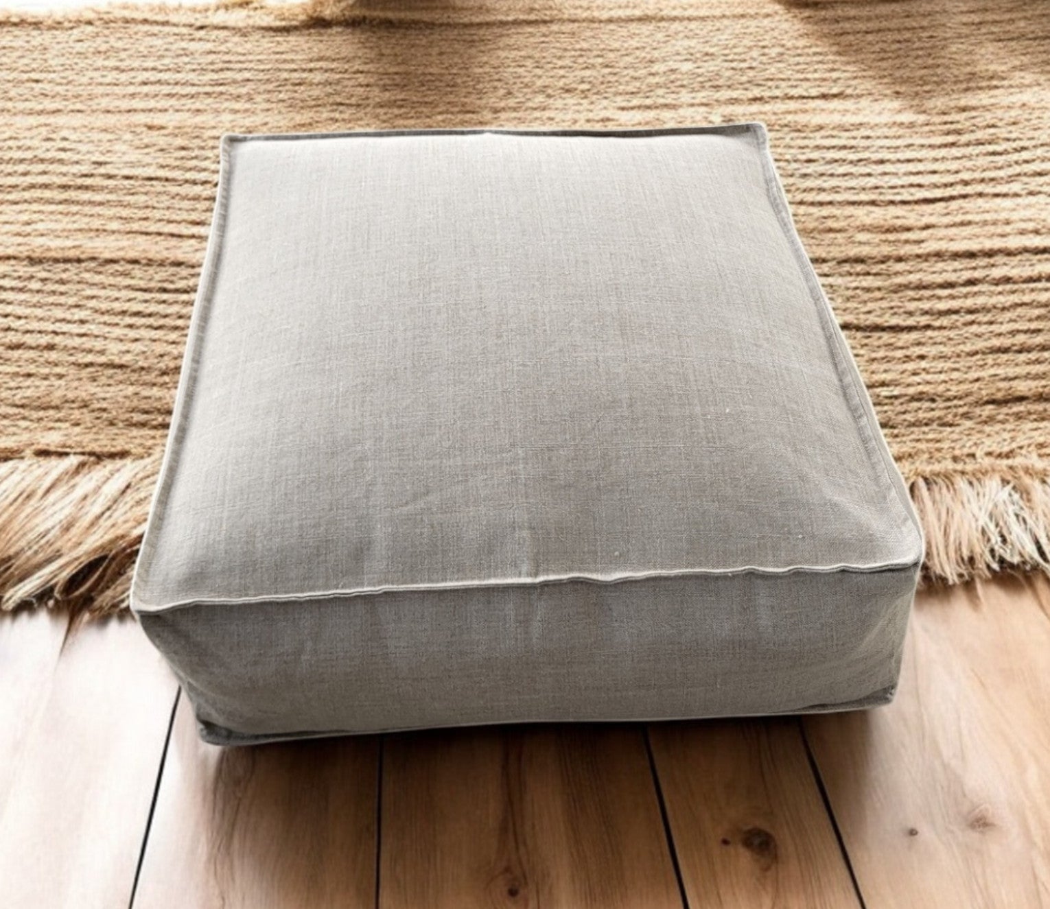 Gray cushion on a wooden floor with a woven rug in the background